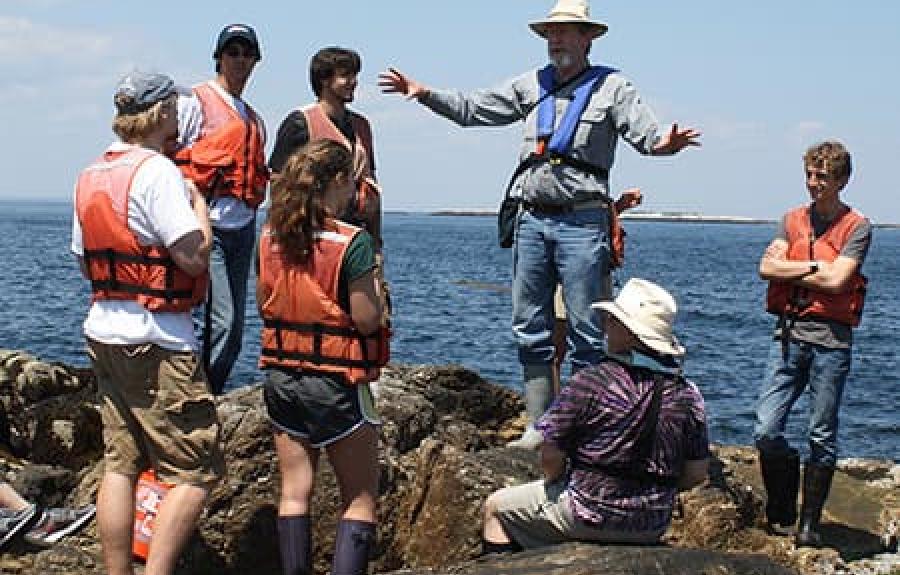 Students on rocks near the water with instructor
