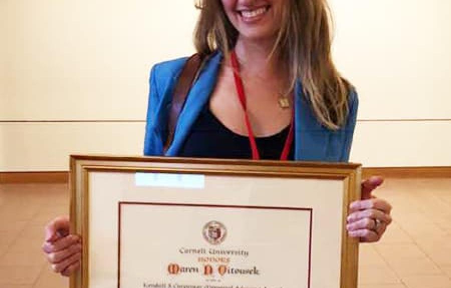 Maren Vitousek holding a framed version of her award