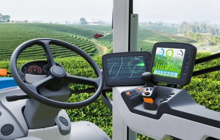 Ag-tech in action; from inside a tractor cabin with digital displays looking out over an agricultural field.
