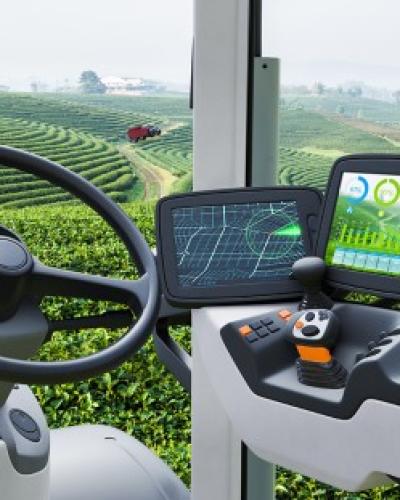 Ag-tech in action; from inside a tractor cabin with digital displays looking out over an agricultural field.