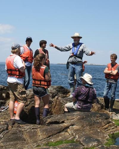 Students on rocks near the water with instructor