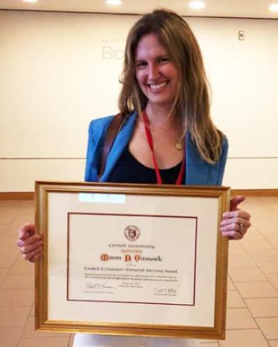 Maren Vitousek holding a framed version of her award